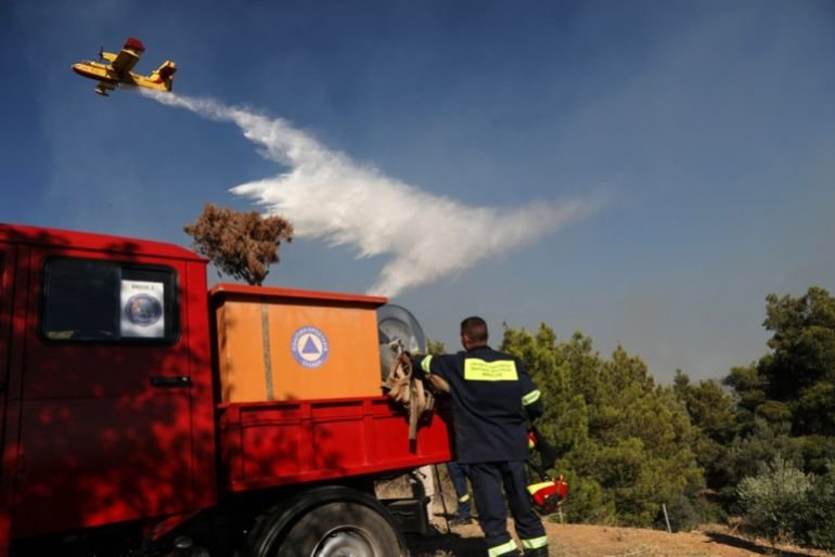 Firefighting aircraft conduct operations over a fire truck during wildfire efforts near Pikermi suburb, east of Athens, Greece, July 3, 2025.