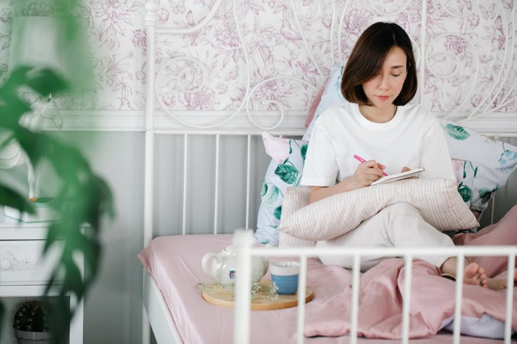 Image of a woman sitting in bed journaling.