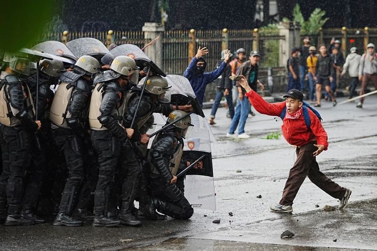 A protester throws a rock at riot police during the protests in Jakarta, Indonesia.